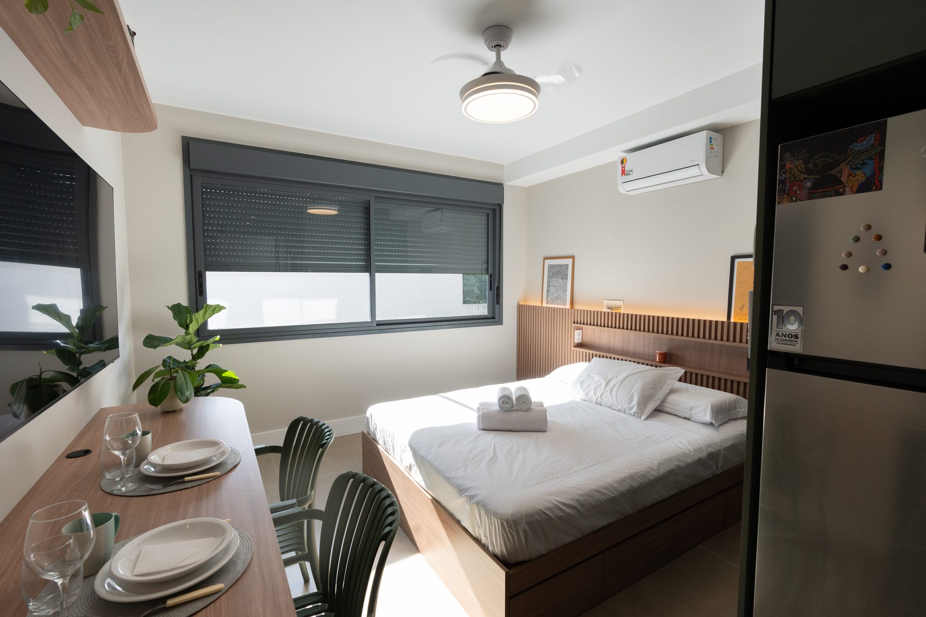Cama queen do Studio 215, com a mesa de jantar em primeiro plano